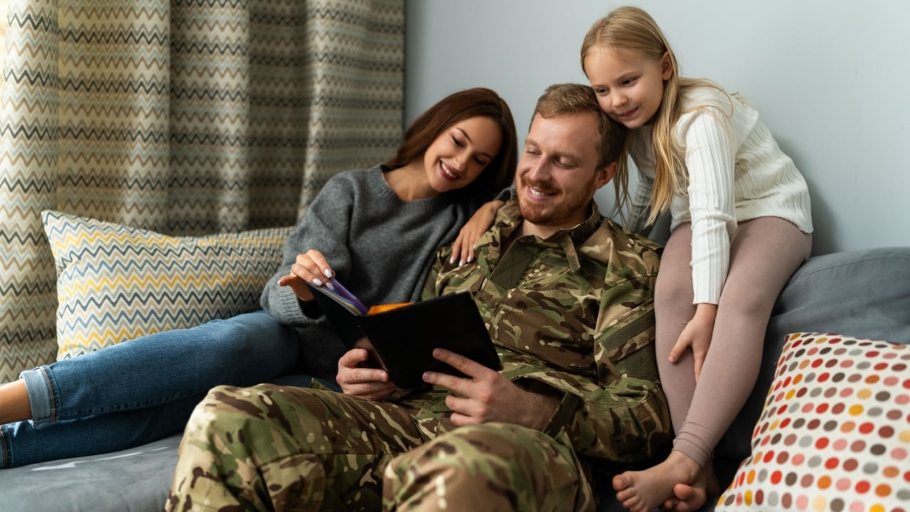 Portrait of military family sitting on the couch at home and watching photo album with happy faces. Happiness concept 