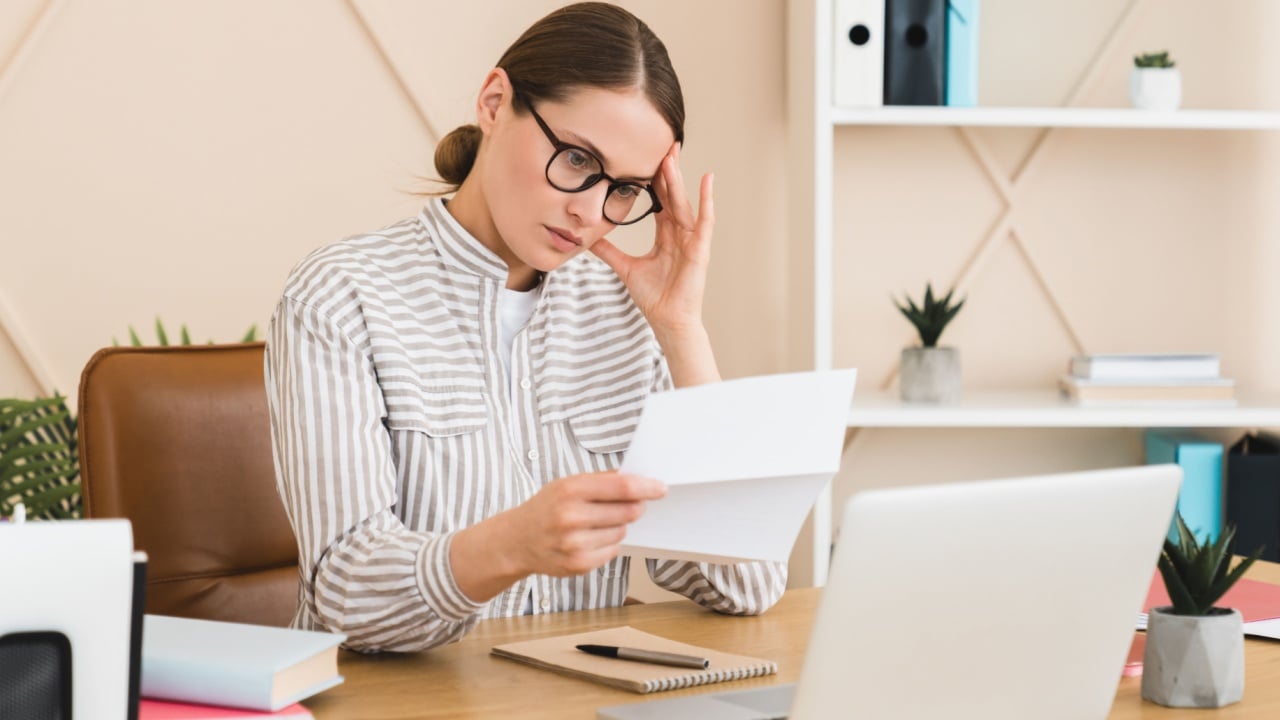 Tired stressed sad young caucasian businesswoman boss freelancer with debt, loan, health problems, test results reading letter, bill. E-commerce, e-banking concept.