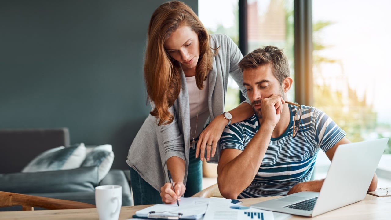 Couple, house and reading with laptop or documents for tax, expenses and debt with interest rate. People, relationship and explain for budget or saving plan for house finance, mortgage and bills