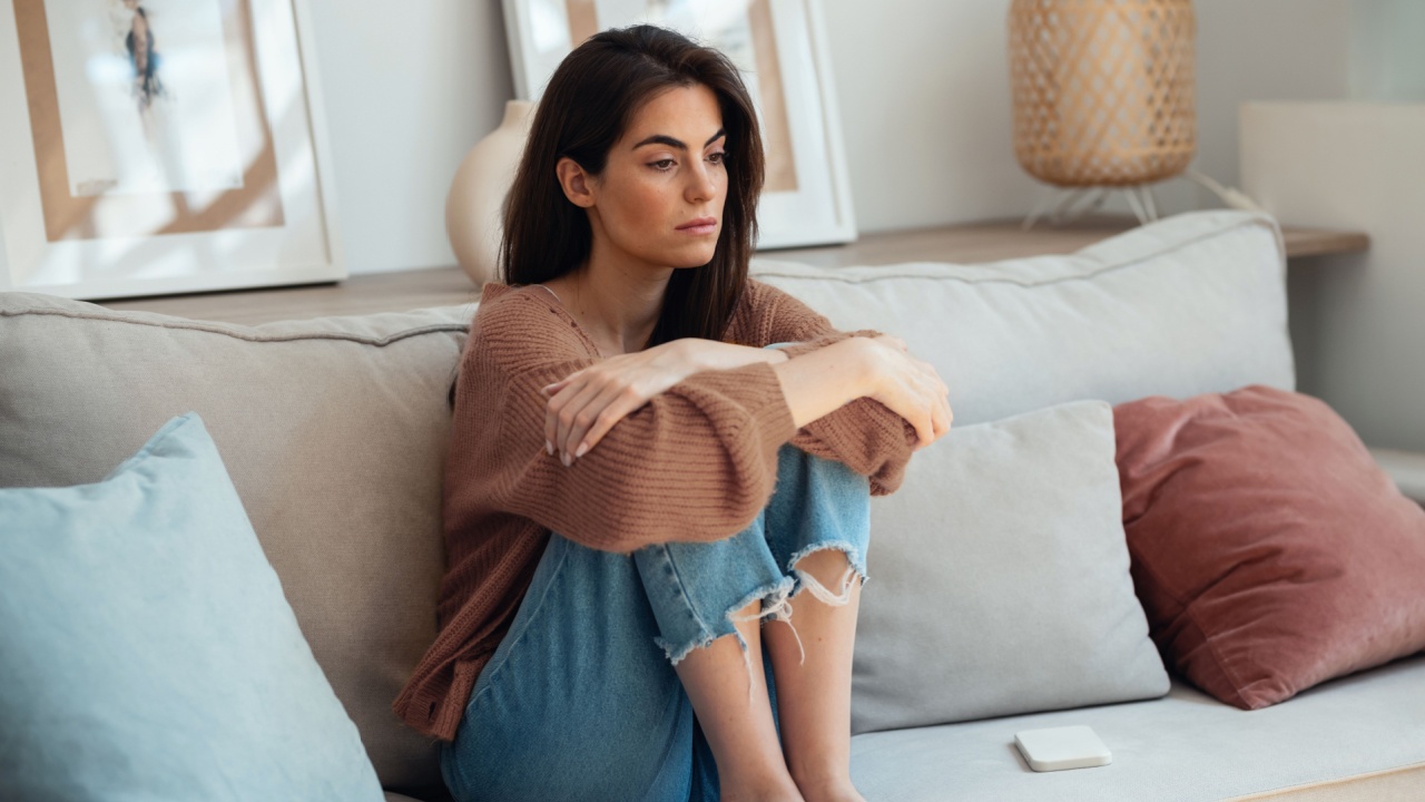 Shot of depressed young woman thinking about her problems while sitting on the sofa at home