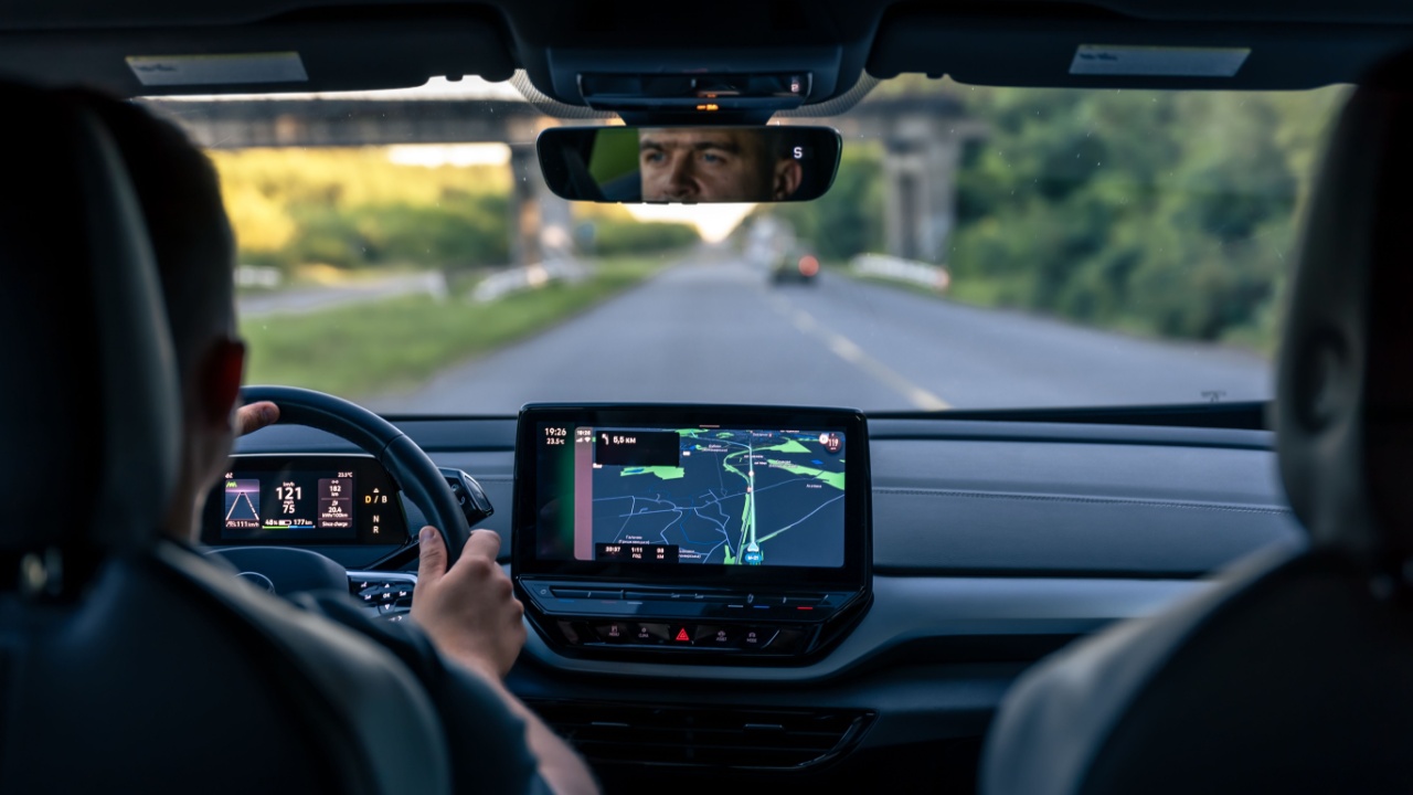 Man touching screen of a GPS navigation system in his car.