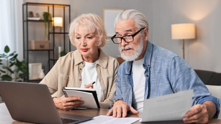 Pension savings. Senior couple planning budget at wooden table indoors