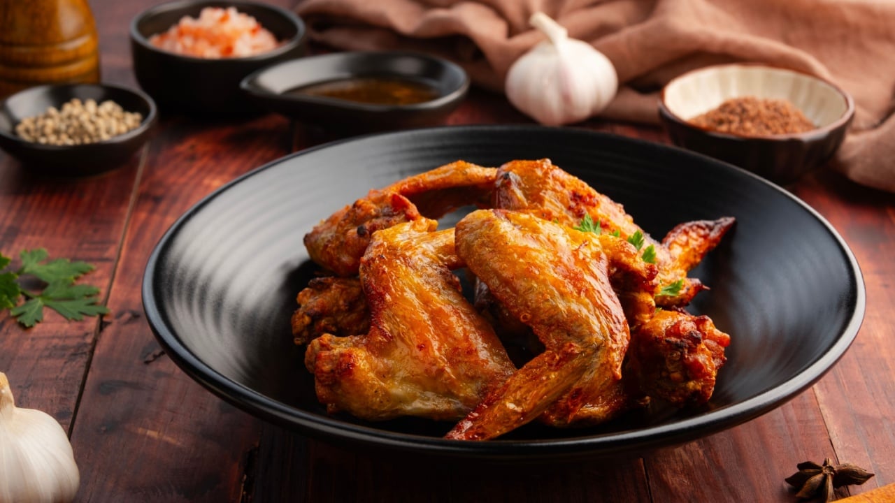 Air Fryer Chicken whole wings (Chicken 3 Joint Wing) with salt in black plate.Crispy and Healthy cooking.