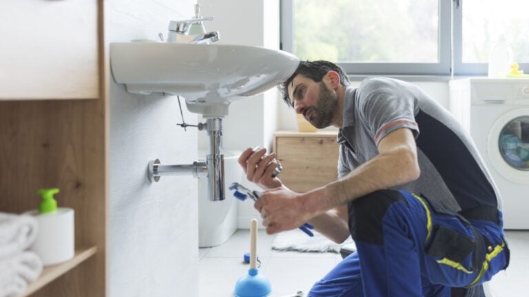 Professional plumber working on a bathroom sink and replacing parts