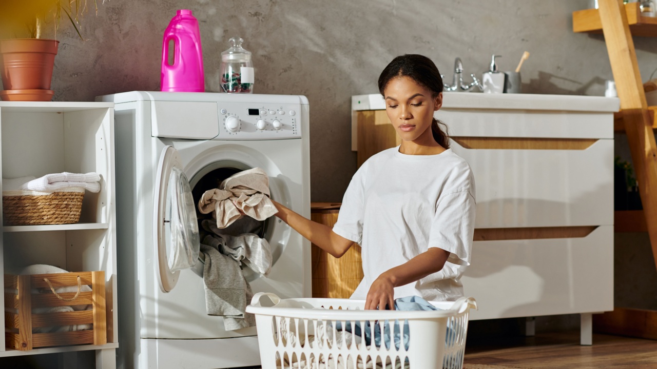 A young African American woman carefully sorts laundry in her stylish apartment space.