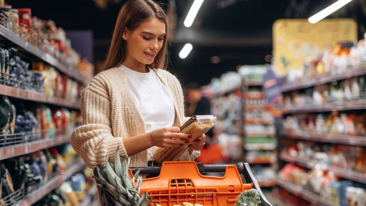 Cart is full. Beautiful woman is in the supermarket.