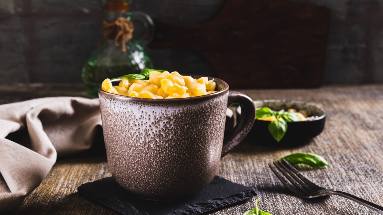Pasta with grated cheese baked in a mug and basil leaves on the table