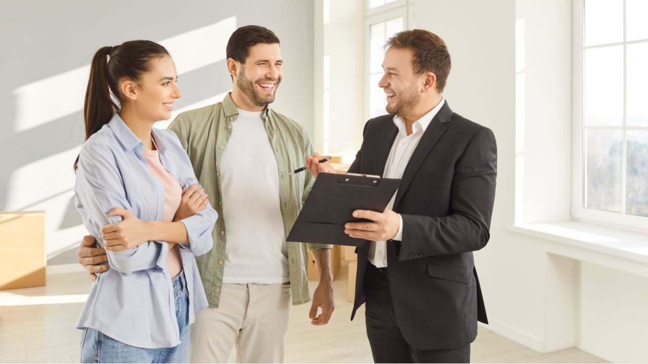 Family couple property investors listening to real estate agent carefully who is giving advice while selling property, beinng shown modern spacious flat or house.