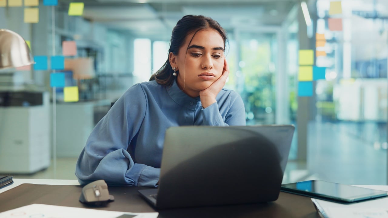 Bored, laptop and tired with business woman at desk in office for administration or planning. Computer, exhausted or fatigue and employee with depression in workplace for compliance or deadline