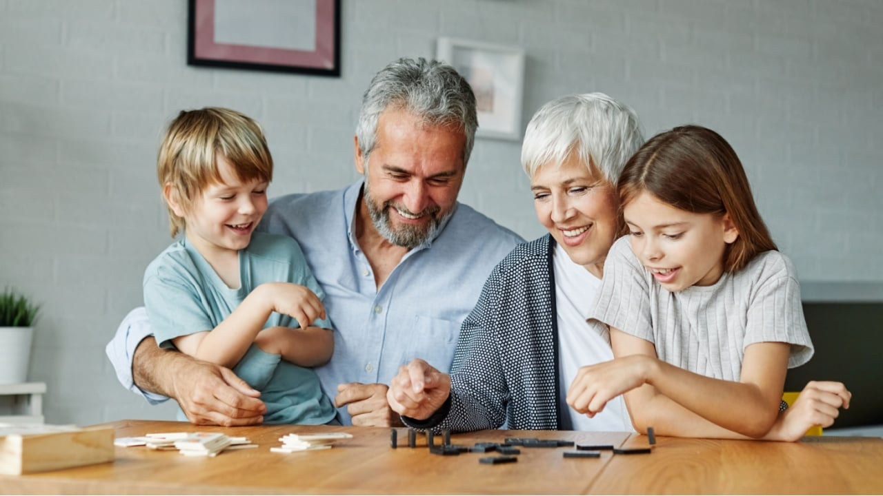 Portrait of grandparents and grandchildren having fun together playing domino game at home