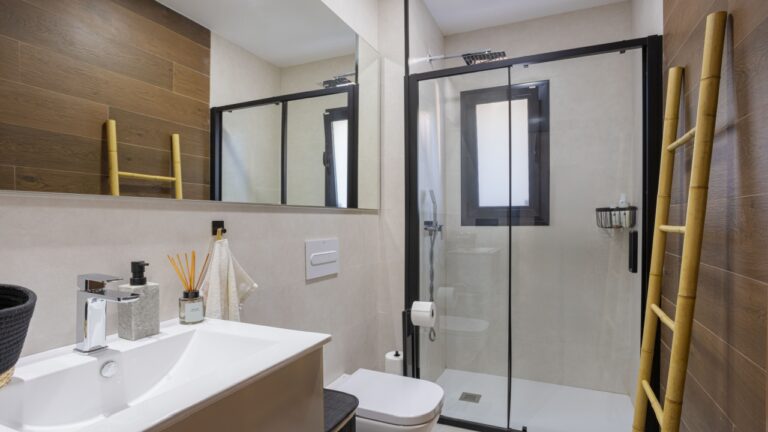 Stylish bathroom featuring a large walk-in shower with glass doors, dual ladders for towels, and warm wooden accents on the walls.