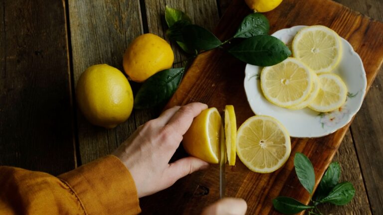 Female hands cutting fresh lemon into slices.