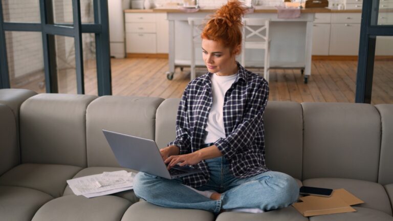 Caucasian woman homeowner girl female at home couch using laptop typing computer check payments bills analyze expenses family budget manage personal money finances loan credit bank mortgage online pay