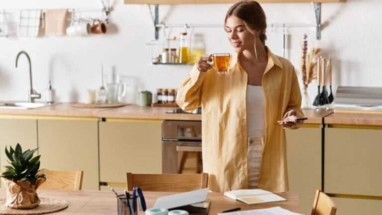 Young woman savoring a cup of tea while standing in her inviting kitchen atmosphere.