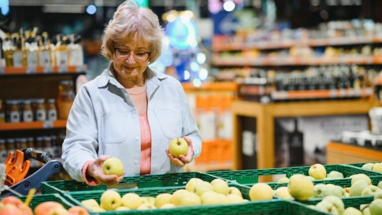 Happy woman is shopping fresh fruits and vegetables at the supermarket.