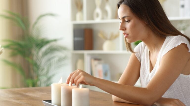 Woman at home lighting candles on a wooden table at home