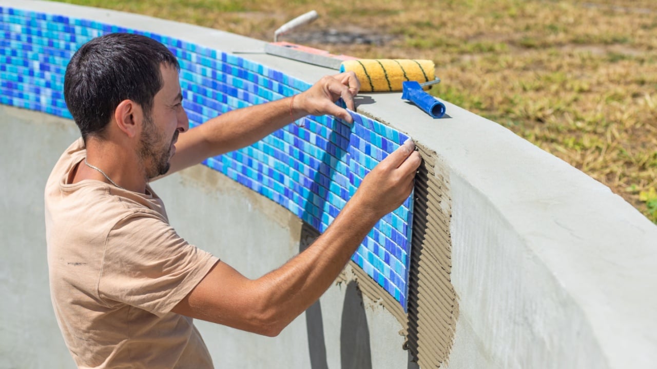 A man lays mosaic tiles in a swimming pool. Selective focus. nature.