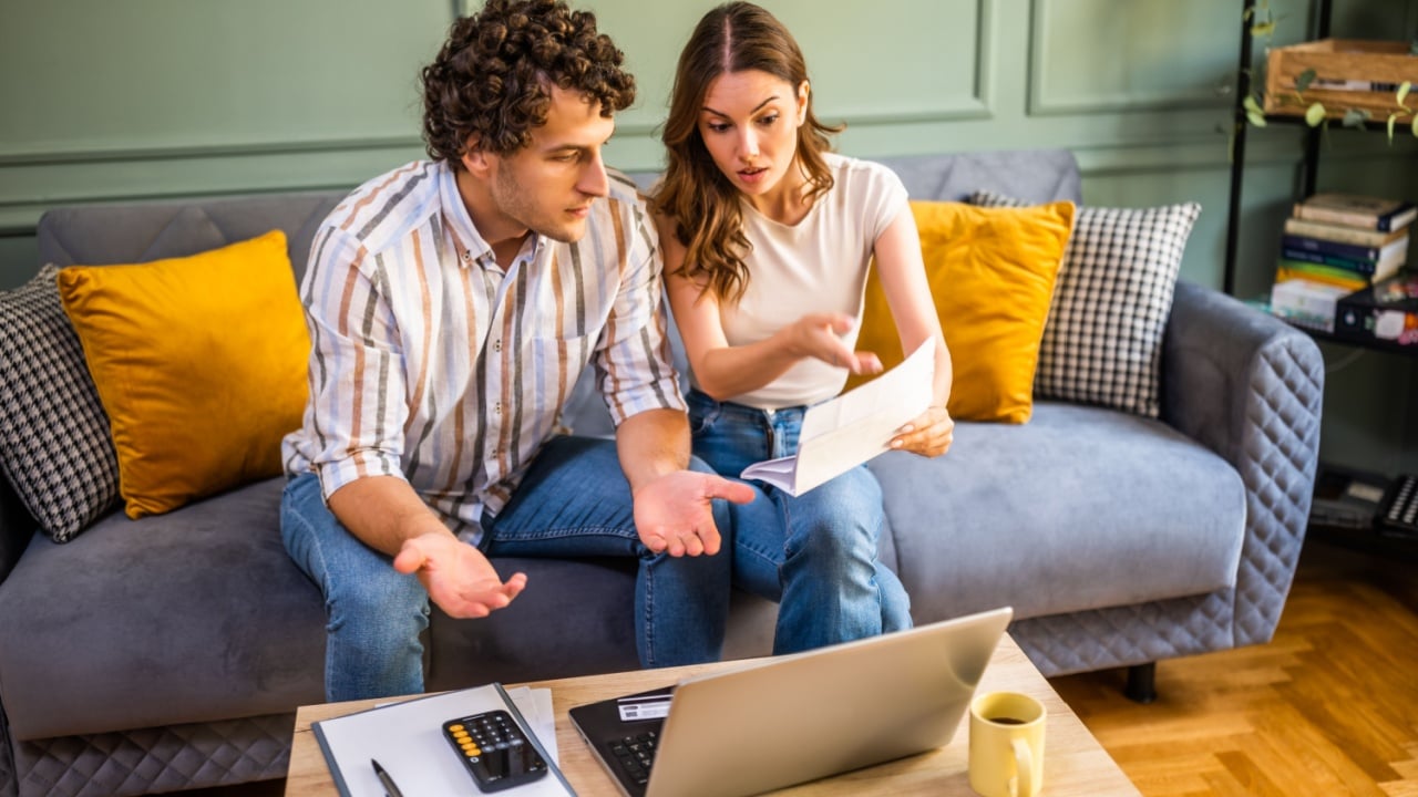Couple discussing home finance while checking bills. They are checking financial documents and calculating family budget in living room.