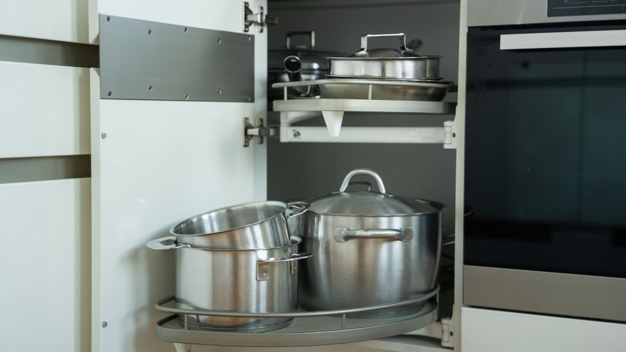 spacious kitchen cabinet showcasing neatly arranged stainless steel cookware including pots and lids on a rotating shelf for optimal storage and accessibility