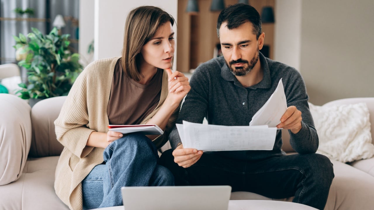 Couple reviewing bills and documents, making financial planning decisions at home