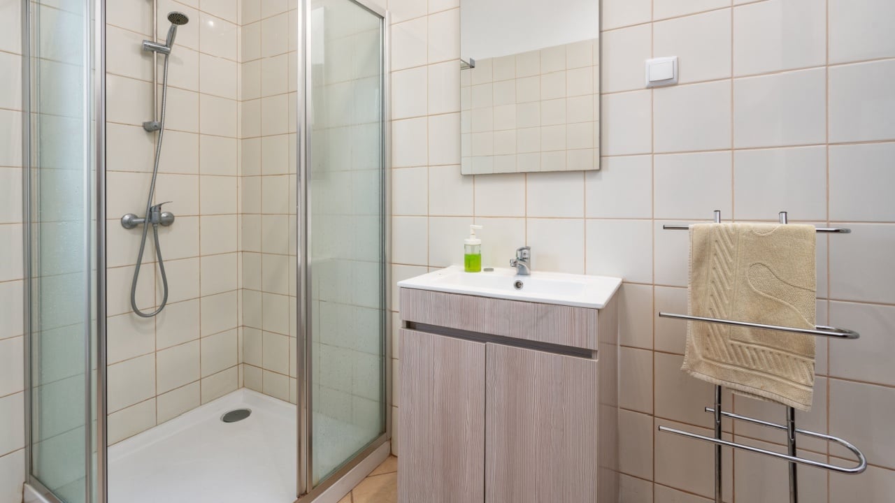 This bathroom features a glass shower stall, a sleek vanity, and neutral tiles, creating a clean and serene environment ideal for relaxation and comfort