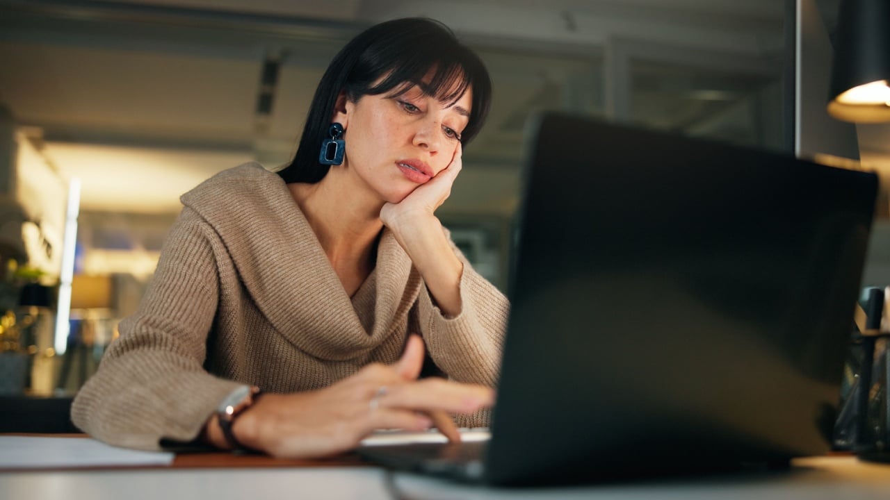 Bored, night or woman in office with laptop, thinking or brain fog in marketing project. Mental health, fatigue and creative director in agency with tech, task deadline and burnout in late shift.