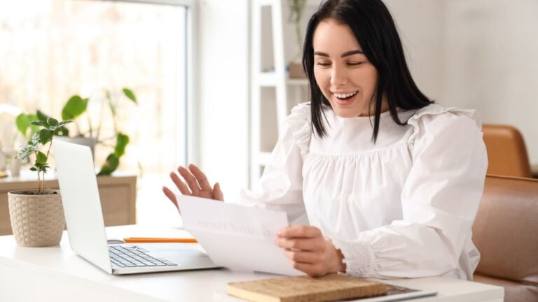 Happy businesswoman with refund form at table in office