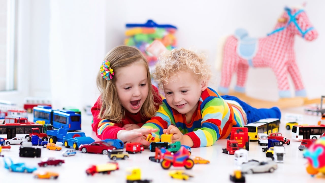 Little toddler boy and girl playing with model car collection on the floor. Transportation and rescue toys for children. Toy mess in child room. Many cars for little boys. Educational games for kids.