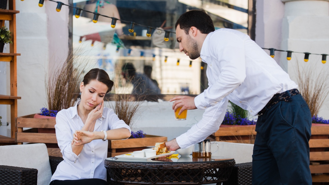 Waiter server at table working reading menu specials list for woman
