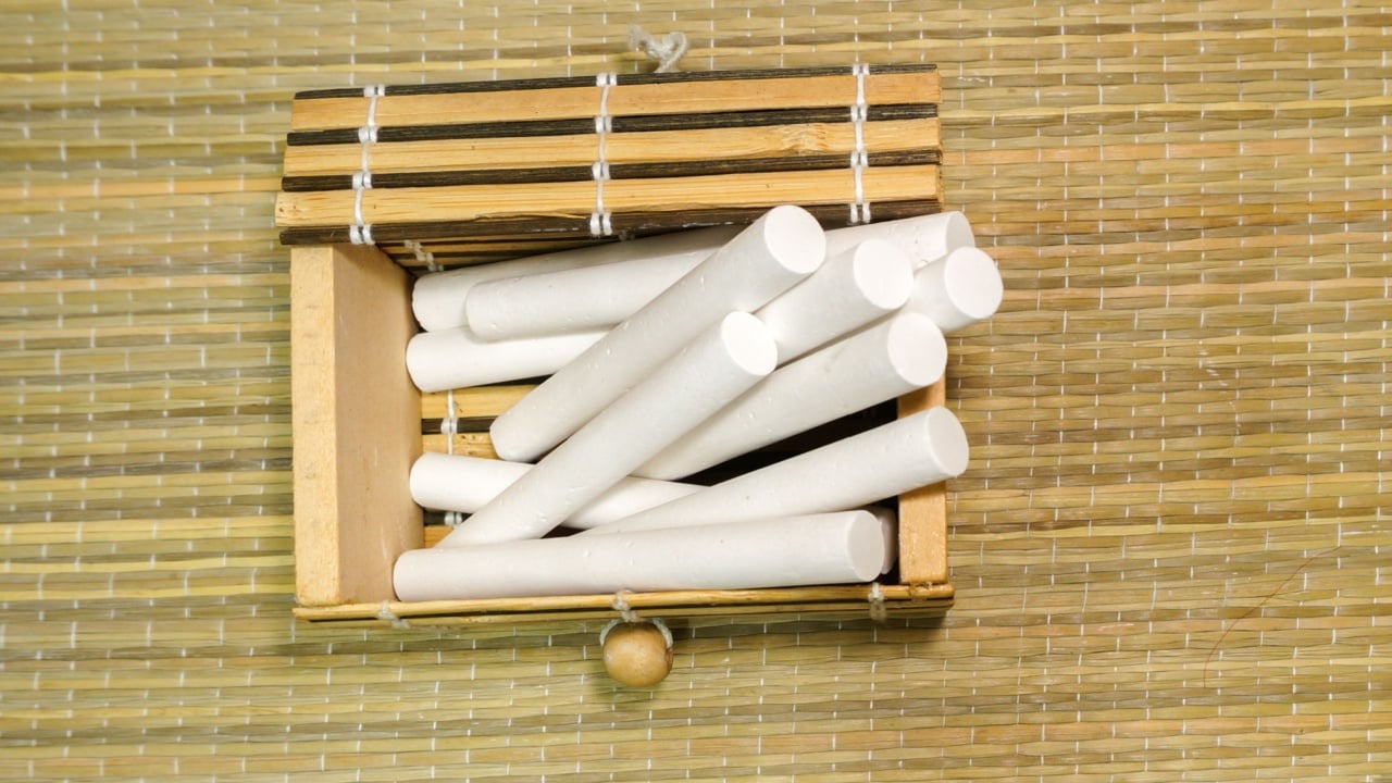 Pile of white chalks inside the wooden container box on bamboo area rugs carpet