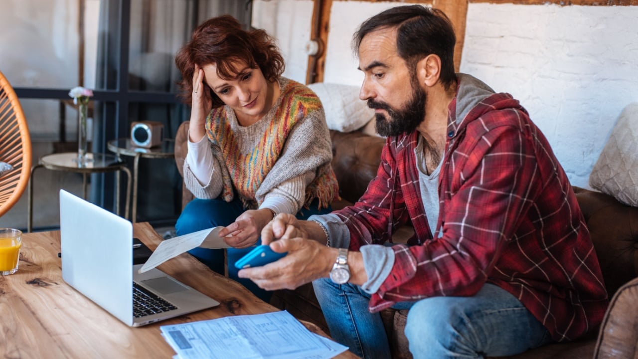Mature couple sitting at home looking at their finance problems