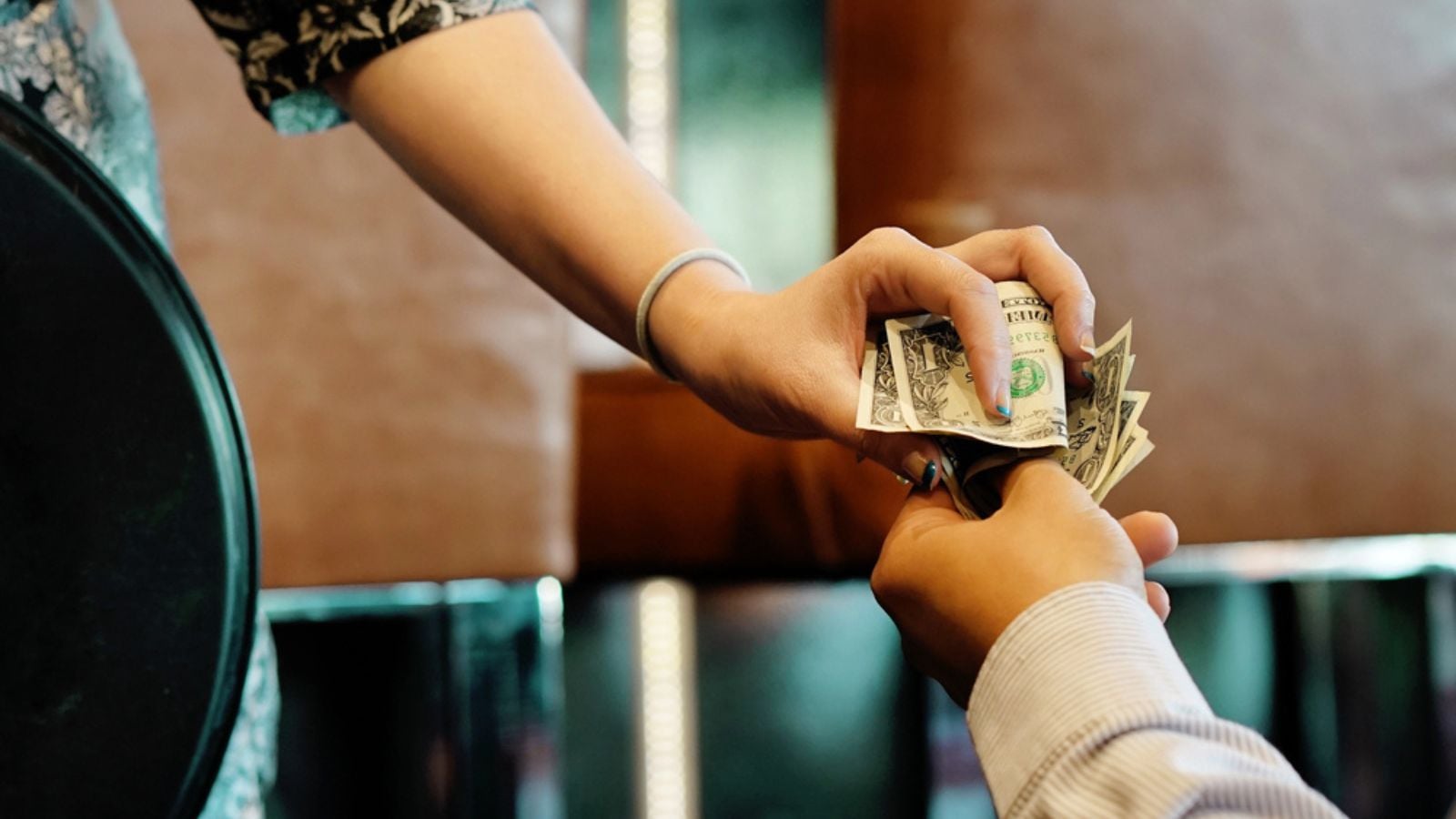The hand of the waitress takes the tip. The waiter girl receives a tip from the client at the hotel bar. A bartender woman is happy to receive a tip at work. The concept of service