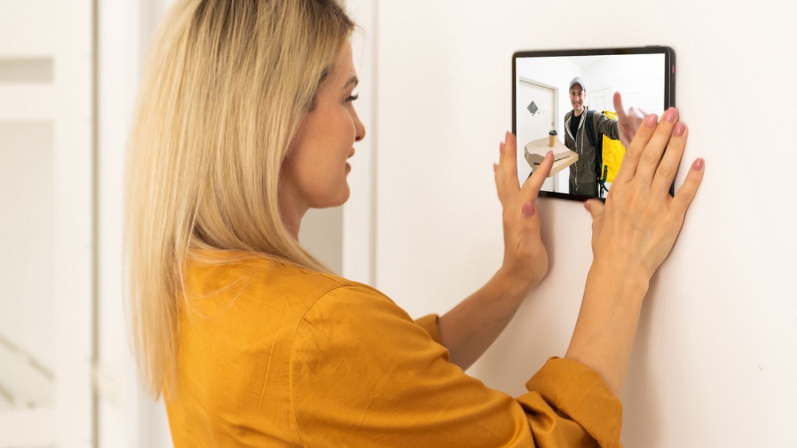 Woman with Security camera system on tablet app - Delivery man holding package in front of door cam