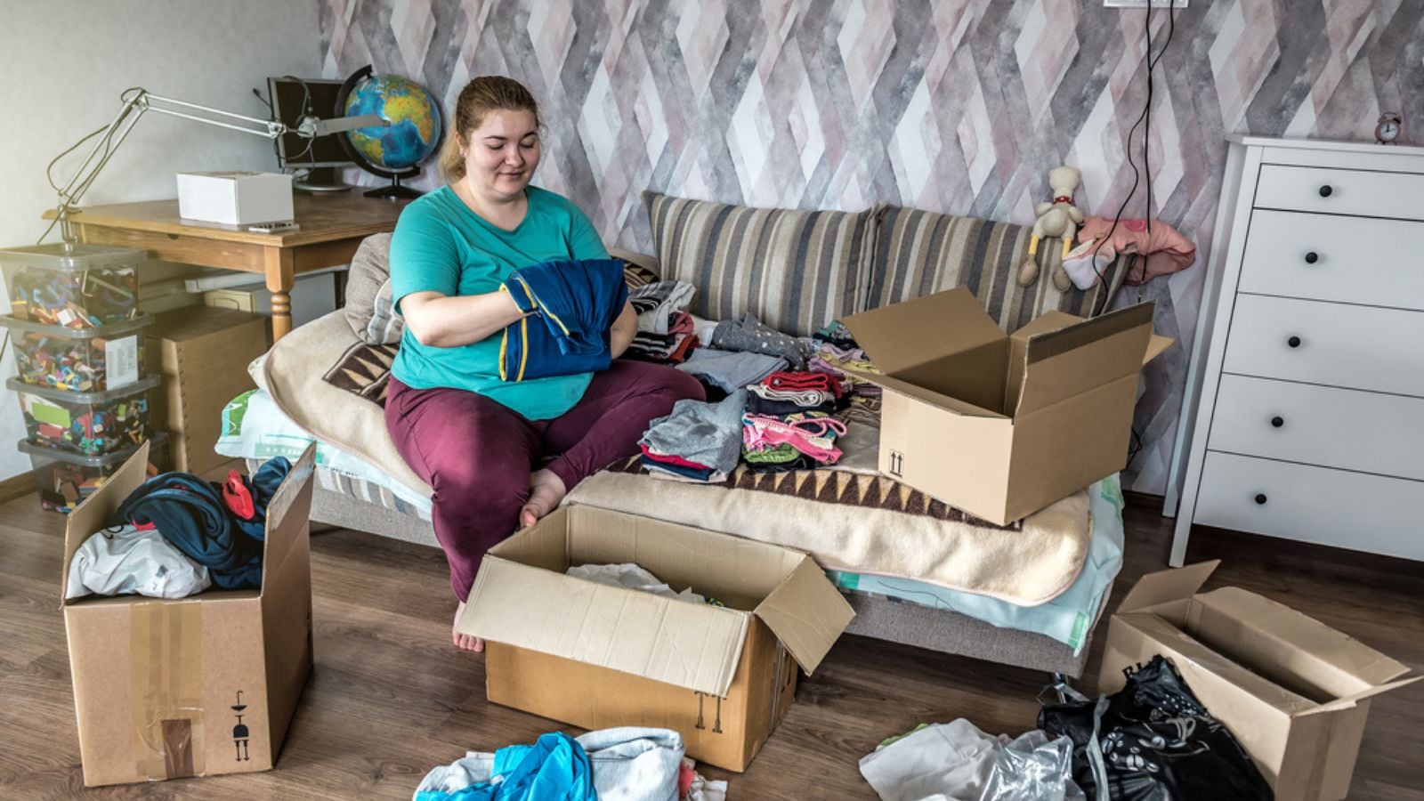 woman sitting on couch sorting clothes donate organize storage