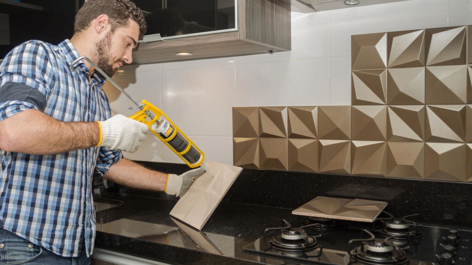 Man renovating, renovating the kitchen, installing tile on the wall backsplash