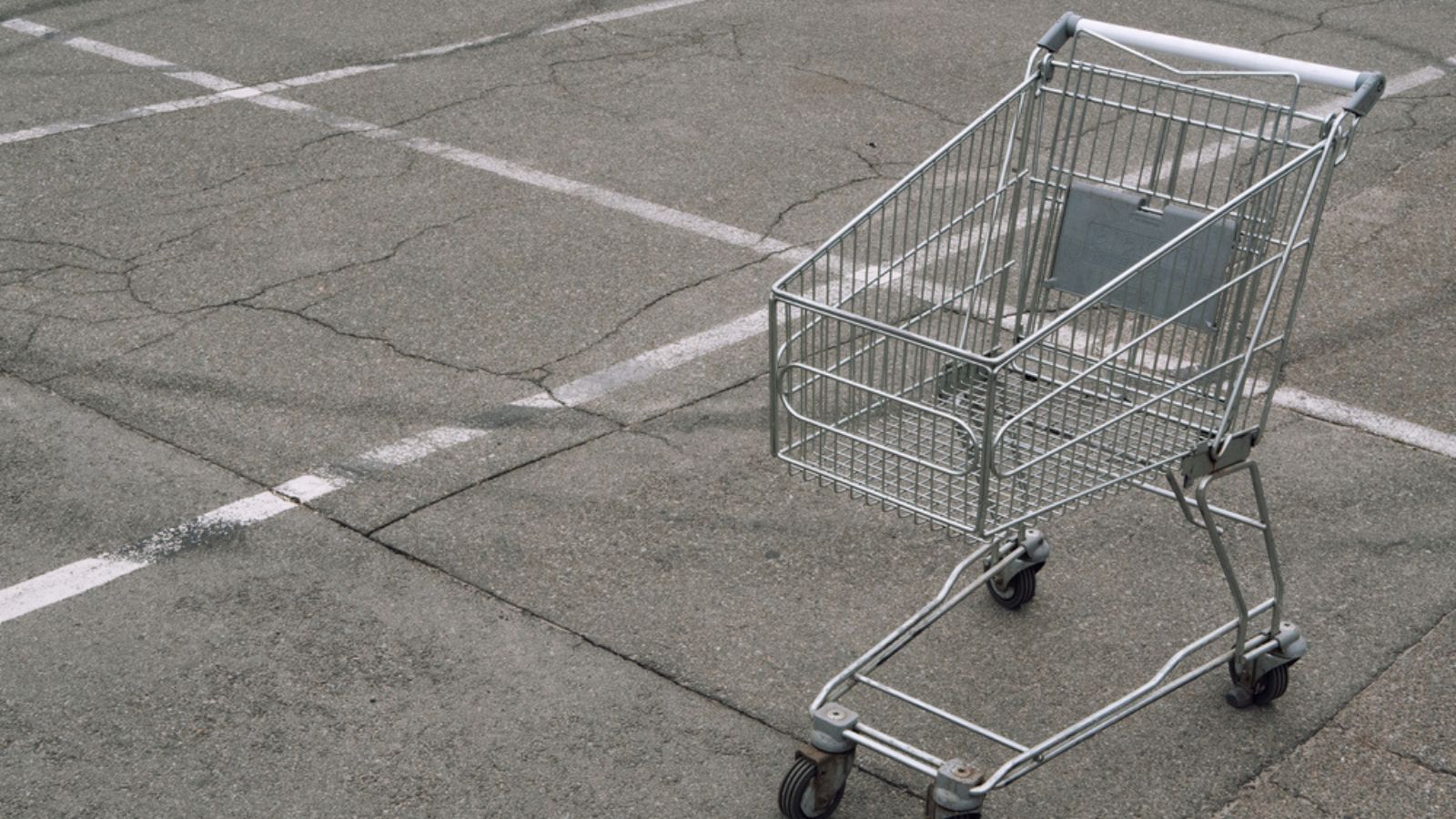 Shopping cart without products goods empty on parking slot near shopping market store mall. lot of copy space