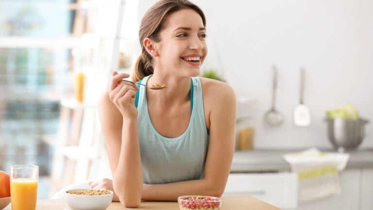 Young woman in fitness clothes having healthy breakfast at home