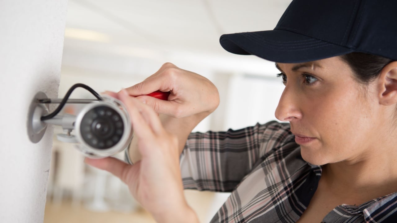 female cctv installer checking security camera