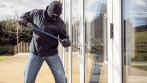 Burglar or thief breaking into a home through window with a crowbar