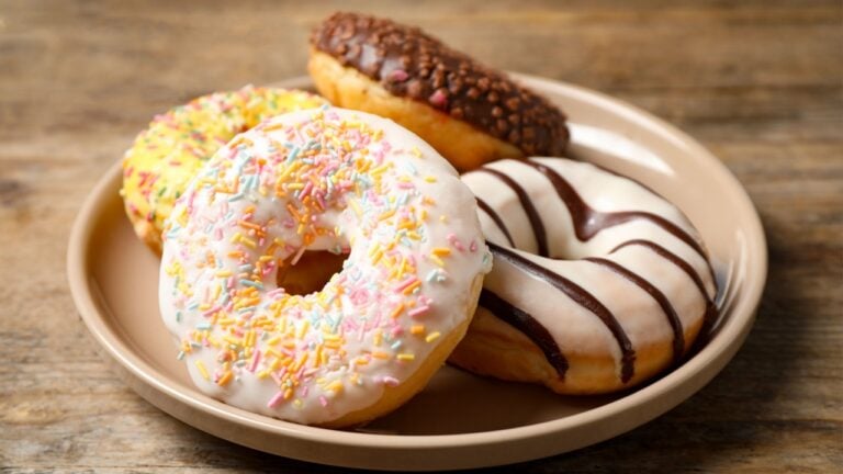 Sweet delicious glazed donuts on wooden table