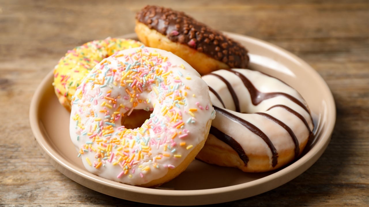 Sweet delicious glazed donuts on wooden table