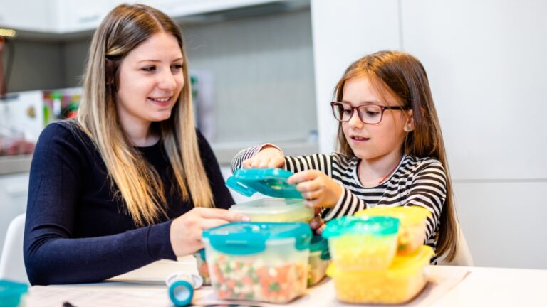 Two sisters working in their home kitchen and preparing vegetables for winter in vacuum containers.