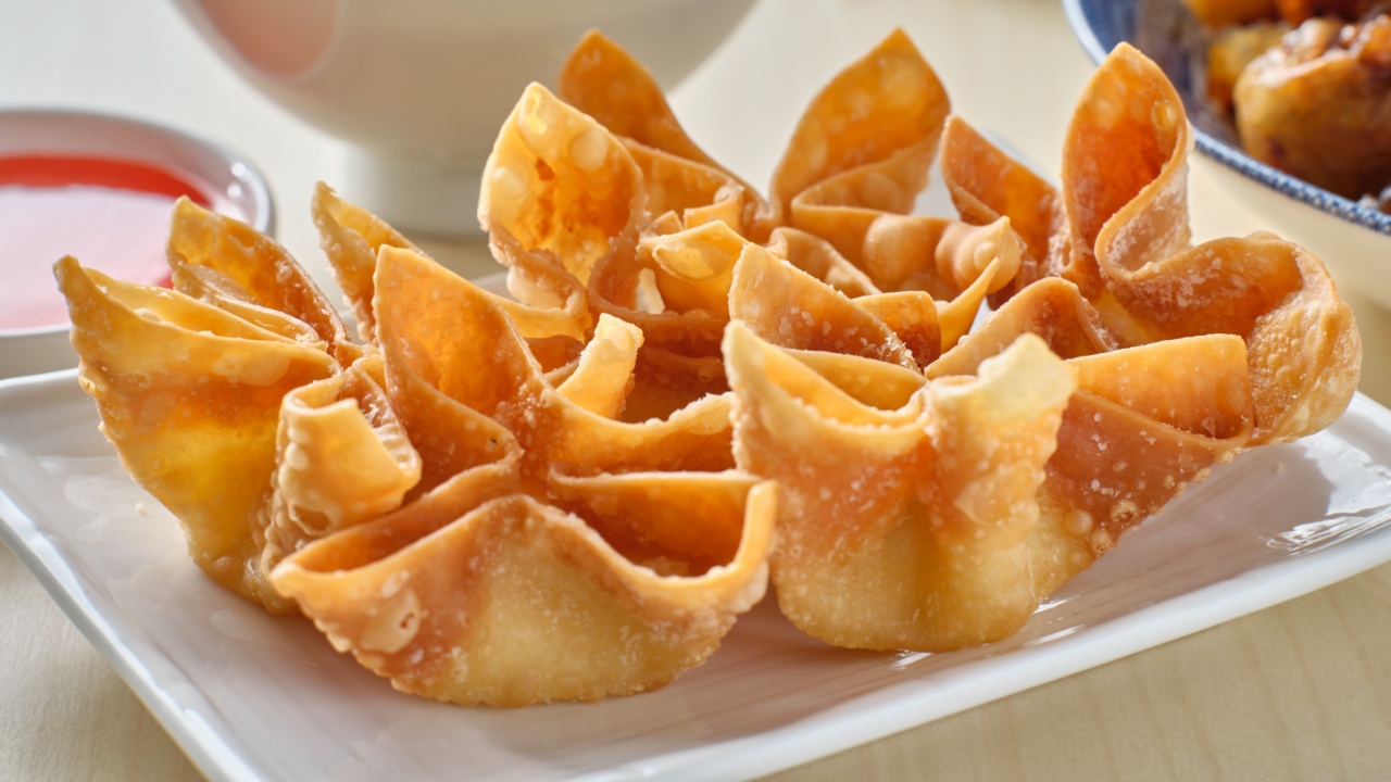 chinese crab rangoon fried wontons on plate with red sauce