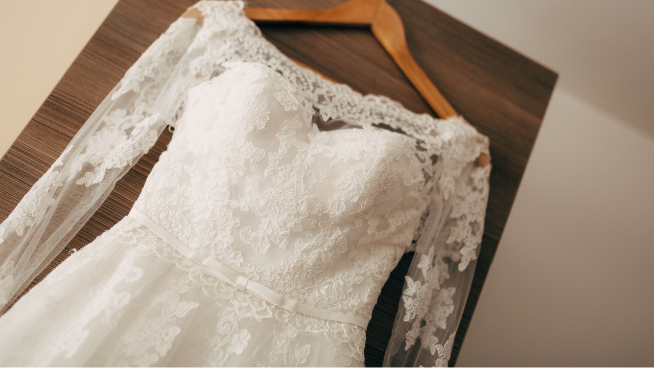 Bridesmaid dress with white thin belts and lace on a wooden texture.