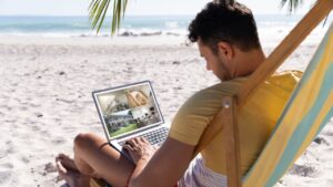 Caucasian man on holidays using laptop with views of home from security cameras on screen. security, safety, surveillance, and digital interface.