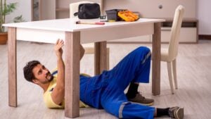 Young male carpenter repairing table at home