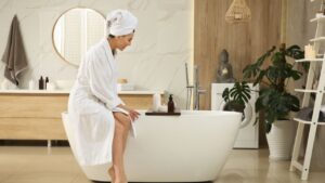 Beautiful young woman sitting on edge of tub in bathroom