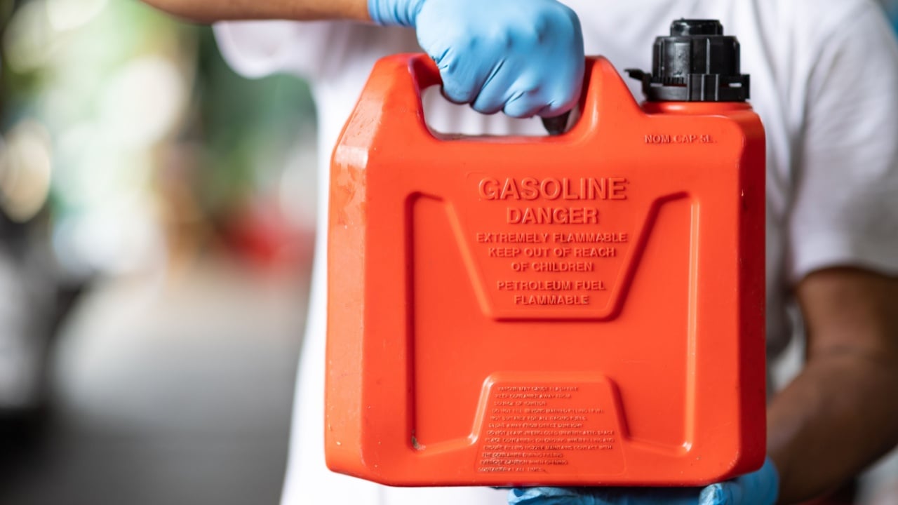 man handle red plastic fuel gallon flammable material container for refill gasoline car tank