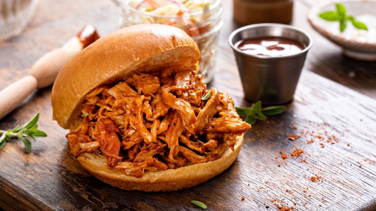 Pulled bbq chicken sandwich on a brioche bun served with cole slaw and bbq sauce