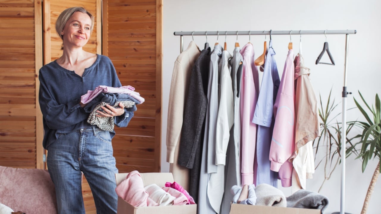 Woman selecting clothes from her wardrobe for recycle or donating to Charity shop. Woman Decluttering Clothes